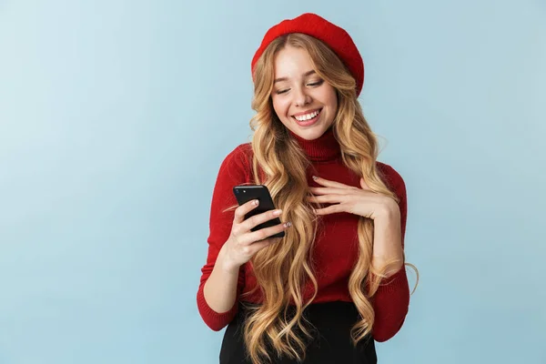 Foto da menina loira 20s vestindo boina vermelha usando smartphone — Fotografia de Stock