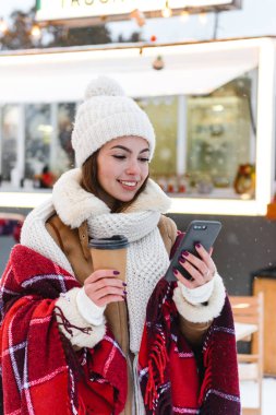 Şapka ve atkı Kışın açık havada yürüyüş genç kadın kar içme kahve.