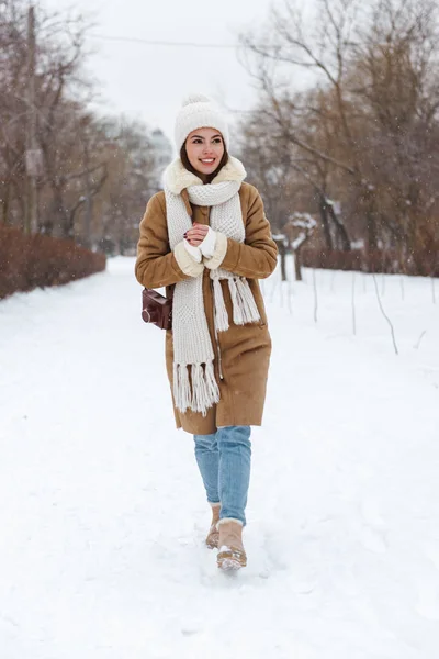 在冬雪中戴帽子和围巾走在户外的年轻女子. — 图库照片