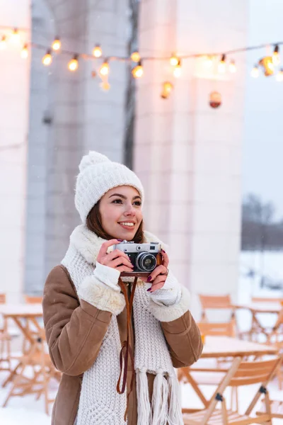 Genç ve güzel kadın fotoğrafçı turist şapka ve atkı açık havada kamera tutarak kış karda yürüme. — Stok fotoğraf
