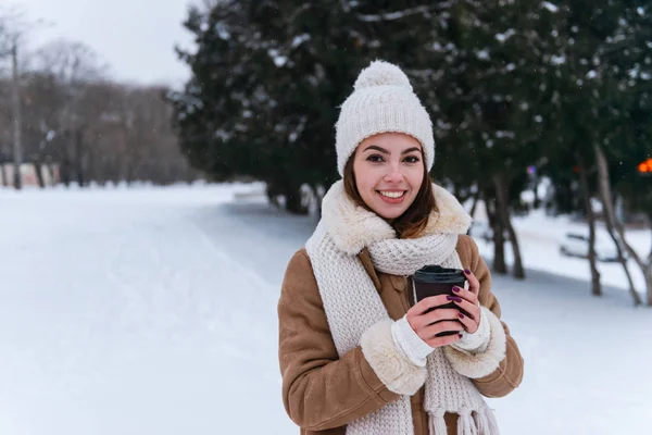 Giovane donna in cappello e sciarpa camminare all'aperto in inverno neve bere caffè . — Foto Stock