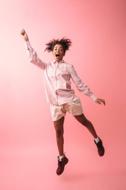 Güzel genç Afrikalı kadın pembe duvar arka plan atlama üzerinde izole poz.