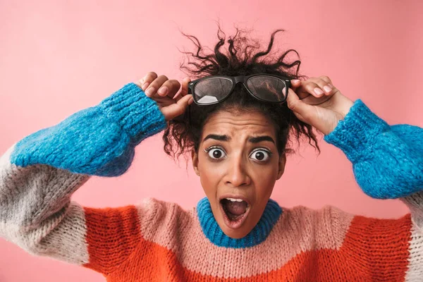 Impresionado emocional hermosa mujer africana joven posando aislado sobre fondo de pared rosa . —  Fotos de Stock