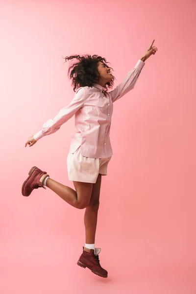 Feliz hermosa joven africana posando aislada sobre fondo de pared rosa . — Foto de Stock