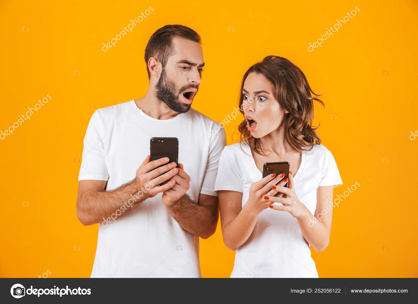 Photo of perplexed man and woman holding and peeking at cell pho Stock ...