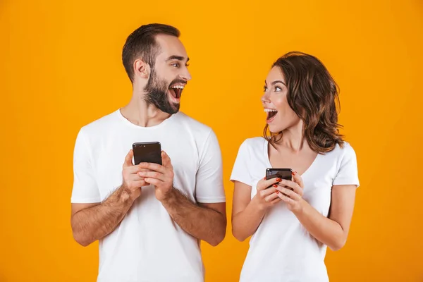 Imagen de pareja excitada hombre y mujer sonriendo mientras ambos usan m — Foto de Stock