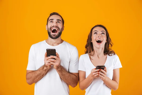 Imagen de pareja alegre hombre y mujer sonriendo mientras ambos usan mo — Foto de Stock