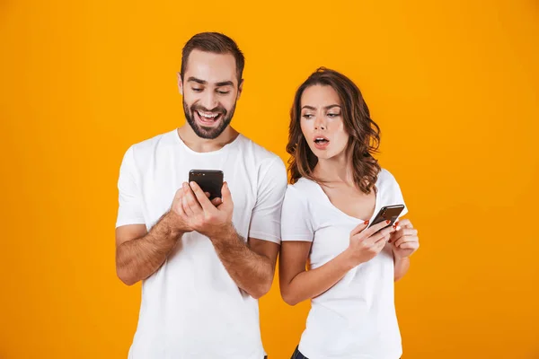 Foto de hombre y mujer excitados sosteniendo y mirando al teléfono celular — Foto de Stock