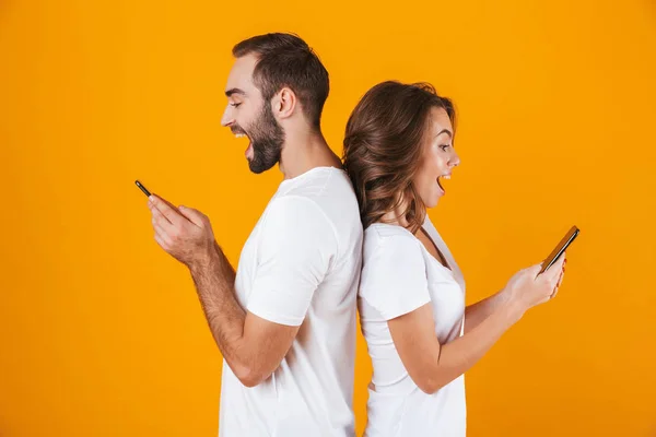 Imagen de pareja feliz sonriendo mientras ambos usan teléfonos inteligentes, isol — Foto de Stock