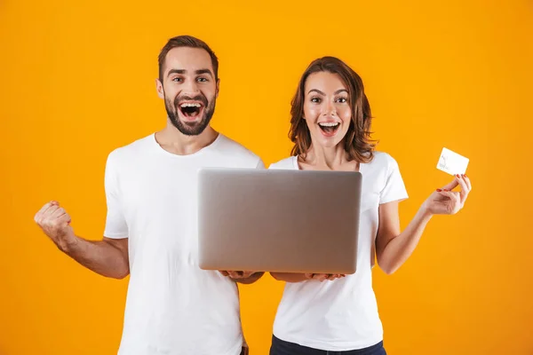Porträtt av ung man och kvinna som håller silver laptop och kredit — Stockfoto