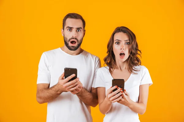 Bilden av chockad par man och kvinna som använder smartphones tillsammans — Stockfoto