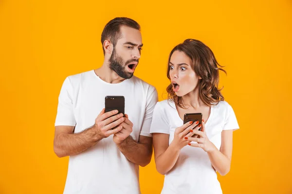 Foto di uomo e donna perplessi che tengono e sbirciano il pho cellulare — Foto Stock