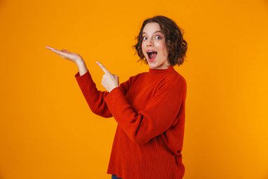 Mutlu duygusal genç güzel kadın boşaltmak gösterilen sarı duvar arka plan üzerinde izole poz.