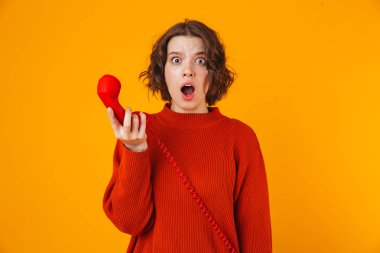 Duygusal genç güzel kadın telefonla konuşuyor sarı duvar arka plan üzerinde izole poz.