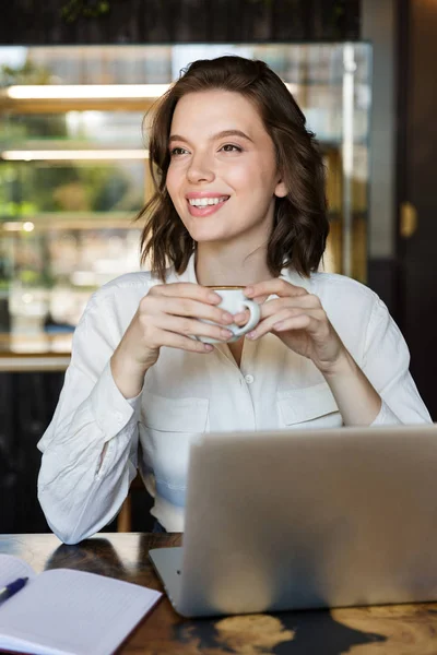 Усміхнена молода бізнес-леді сидить у кафе в приміщенні — стокове фото