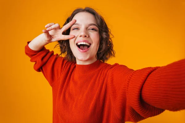 Nadšený šťastný emocionální mladého hezká žena představuje samostatný žlutý zdi pozadí focení sebe ukazující mírové gesto. — Stock fotografie