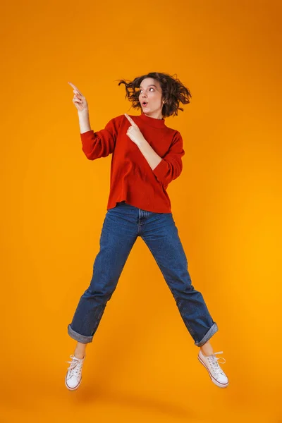 Feliz emocional joven bonita mujer posando aislada sobre fondo amarillo de la pared que muestra copyspace . — Foto de Stock