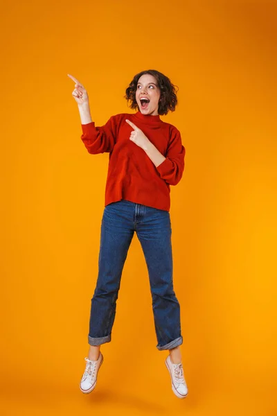 Feliz emocional joven bonita mujer posando aislada sobre fondo amarillo de la pared que muestra copyspace . —  Fotos de Stock