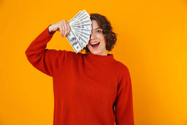 Opgewonden gelukkig jonge mooie vrouw poseren geïsoleerde over gele muur achtergrond aanhouden van geld. — Stockfoto