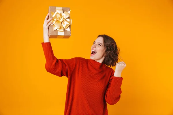 Emotionele jonge mooie vrouw poseren geïsoleerde over gele muur achtergrond bedrijf aanwezig cadeau. — Stockfoto