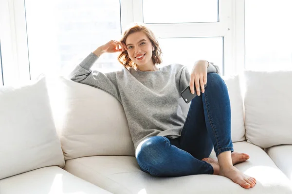 Bella sorridente giovane donna rilassante su un divano — Foto Stock
