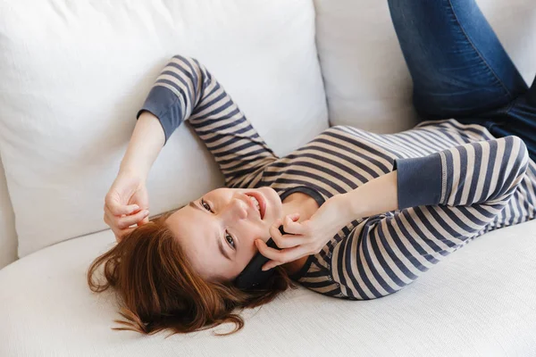 ソファの上でリラックスした笑顔の美しい若い女性 — ストック写真