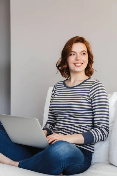 Schöne lächelnde junge Frau entspannt sich auf einer Couch — Stockfoto