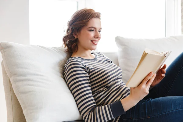 Hermosa joven sonriente relajándose en un sofá — Foto de Stock