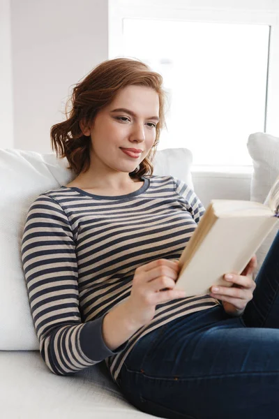 Hermosa joven sonriente relajándose en un sofá —  Fotos de Stock