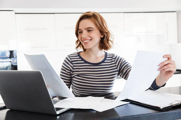 Улыбающаяся молодая женщина, работающая за ноутбуком — стоковое фото