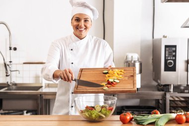 Fotoğraf gülümseyen kadın Şef giyen beyaz üniforma salatası w yapmak