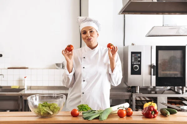 Photo of amusing woman chef wearing white uniform cooking meal w — Stock Photo, Image