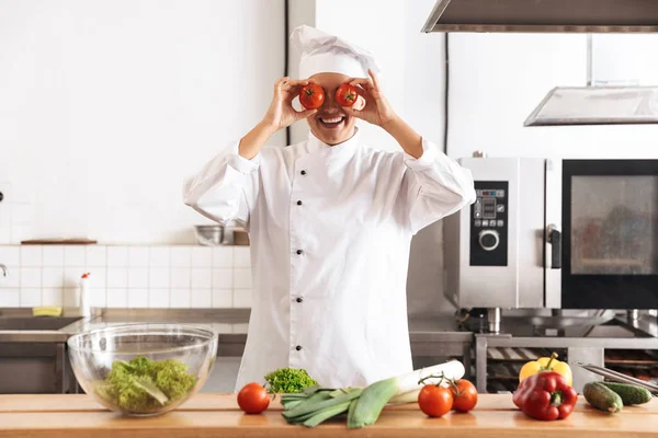 Foto de la mujer alegre chef con uniforme blanco comida de cocina —  Fotos de Stock