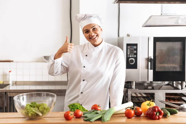 Photo of happy woman chef wearing white uniform cooking meal wit