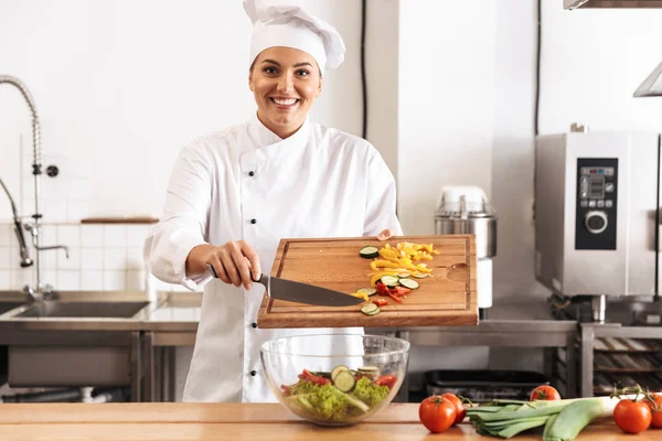 Фото усміхненої жінки шеф-кухаря в білій формі робить салат w — стокове фото