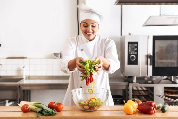 Photo de femme joyeuse chef portant un uniforme blanc faisant de la salade wi — Photo