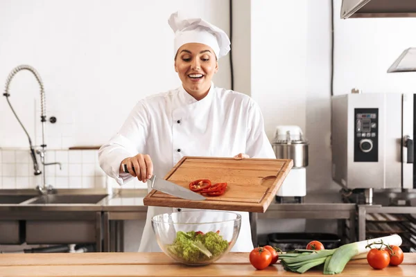 Photo d'une femme chef positive portant un uniforme blanc faisant de la salade — Photo