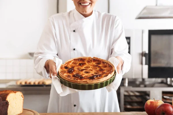 Bild einer lächelnden Köchin in weißer Uniform mit Apfel — Stockfoto