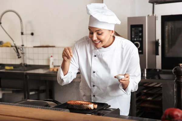 Smiling woman chef cook wearing uniform cooking