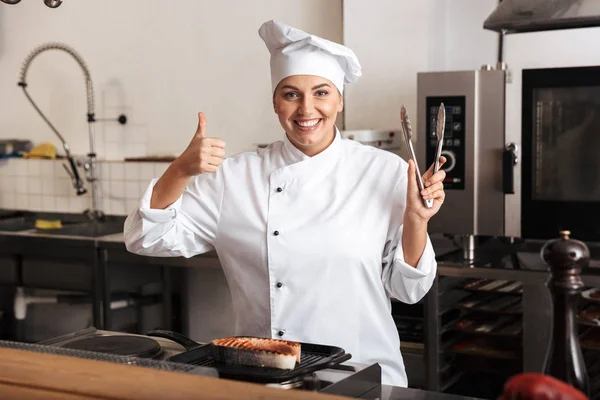 Uśmiecha się kobieta kucharz sobie jednolite gotowanie potraw — Zdjęcie stockowe