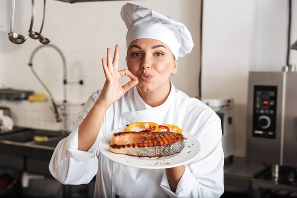 Image d'une cuisinière européenne portant un uniforme blanc, tenant une assiette — Photo