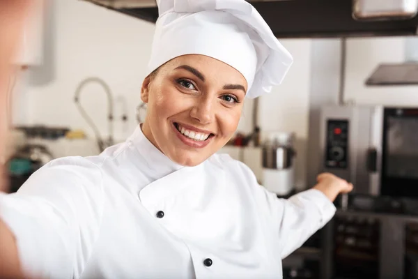 Retrato de mujer positiva chef vistiendo uniforme blanco, tomando se — Foto de Stock