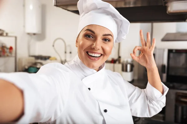 Portrait of beautiful woman chef wearing white uniform, taking s