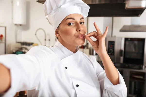 Ritratto di donna chef divertente che indossa uniforme bianca, prendendo selfi — Foto Stock