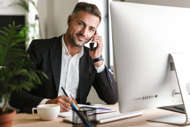 Çalışma o sırasında cep telefonuyla konuşurken mutlu işadamı görüntüsü
