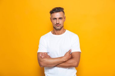 Ciddi yakışıklı sarı duvar arka plan üzerinde izole poz.