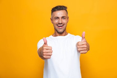 Duygusal yakışıklı izole jest Yaşasın gösterilen sarı duvar arka plan üzerinde poz.