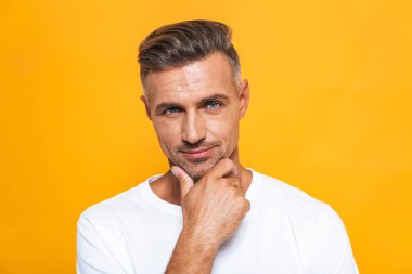 Ciddi yakışıklı sarı duvar arka plan üzerinde izole poz.