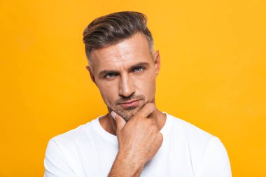 Ciddi yakışıklı sarı duvar arka plan üzerinde izole poz.