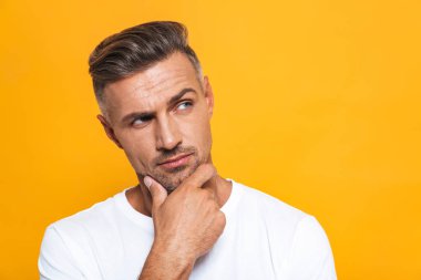 Ciddi yakışıklı sarı duvar arka plan üzerinde izole poz.